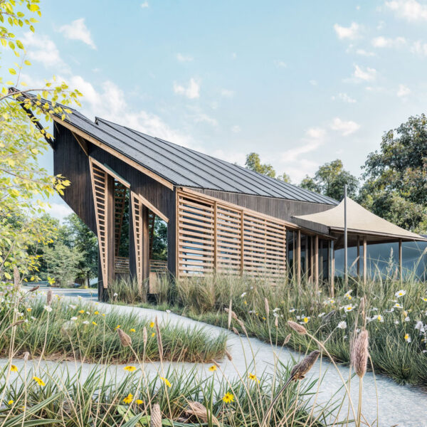 Eco-conscious wooden structure with solar roof beside Pilsworth Lake, surrounded by wetland and greenery.
